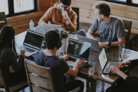 Team arbeitet gemeinsam am Laptop in einem hellen Büro